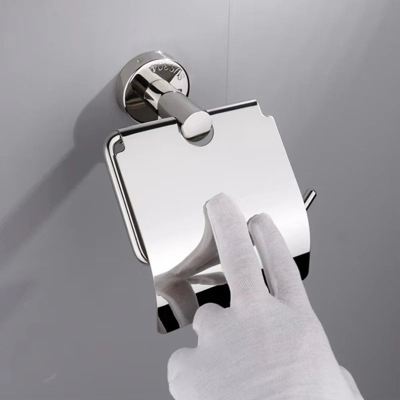 A side-angle product photo of a high-polish silver stainless steel covered toilet paper holder, with a single roll of white toilet paper.